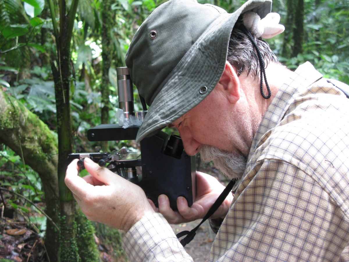 Global Focus Microscope in field use — researcher peering through the rugged, low-cost diagnostic scope